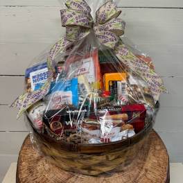Gift basket of assorted snacks wrapped in clear cellophane with a decorative bow