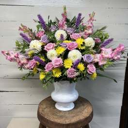 Large mixed bouquet in a white vase with pink, purple, and yellow flowers
