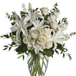 White lilies and roses arranged in a clear glass vase