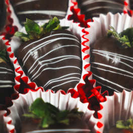 Box of chocolate-covered strawberries in red and white paper cups