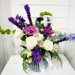 Purple and white mixed flower arrangement in a blue vase