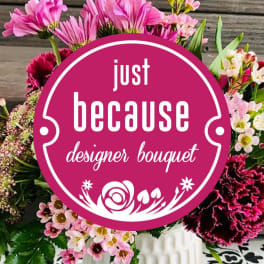 Mixed pink and white bouquet behind a round "just because" sign