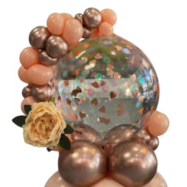 Balloon arrangement with a clear confetti balloon and a peach flower accent
