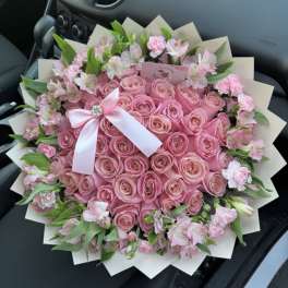 Pink rose bouquet with a white ribbon and small pink flowers