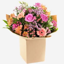 Mixed bouquet of pink and peach flowers in a tan box