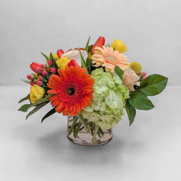 Mixed bouquet in a clear glass vase with orange and peach blooms