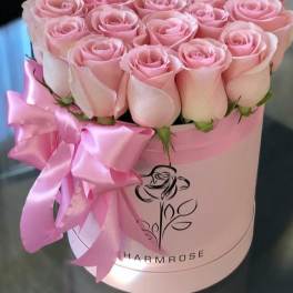 Pink roses arranged in a round hat box with a satin ribbon