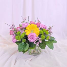 Pink and yellow flower arrangement in a clear glass vase