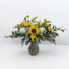 Yellow sunflowers and white roses in a textured glass vase