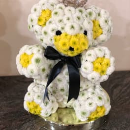 Teddy bear made of white and yellow flowers with a black ribbon