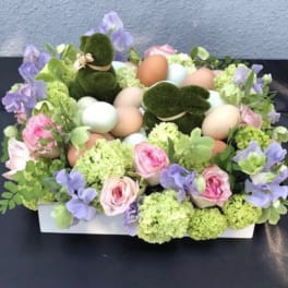 Pastel floral arrangement with eggs and moss bunny figures in a white box