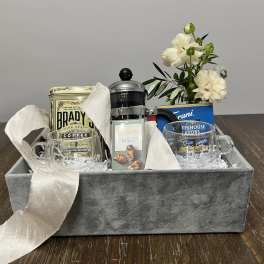 Gift basket with coffee, mugs, tea, and white flowers