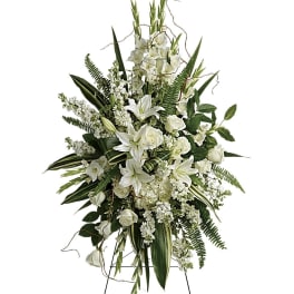 White floral standing spray on an easel with lilies and roses