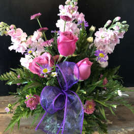 Pink roses and purple flowers arranged with a purple ribbon