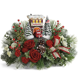 Christmas arrangement with red roses, pinecones, and a miniature snowy house