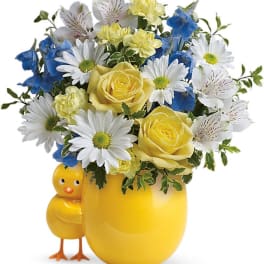 Yellow vase with a chick figurine holding daisies, roses, and blue flowers