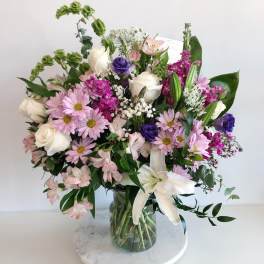 Mixed bouquet of pink, white, and purple flowers in a glass vase