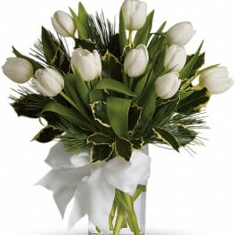 White tulips arranged in a glass vase with a white ribbon
