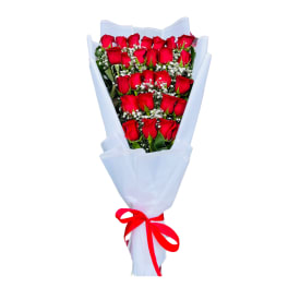 Tall bouquet of many red roses with small white filler flowers wrapped in white paper and tied with a red ribbon