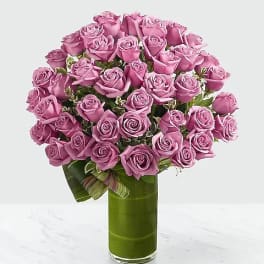 Pink roses arranged in a tall glass vase with a ribbon