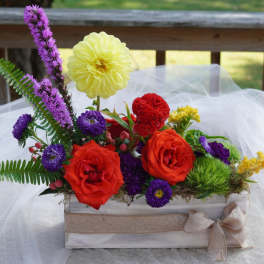 Colorful flower arrangement in a white wooden box with a burlap bow