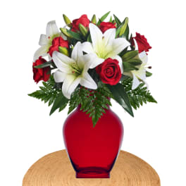 Red roses and white lilies arranged in a red vase