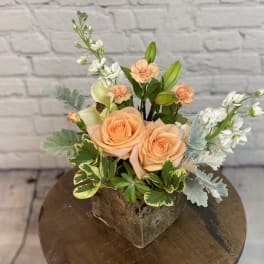 Peach roses and white flowers in a square rustic container
