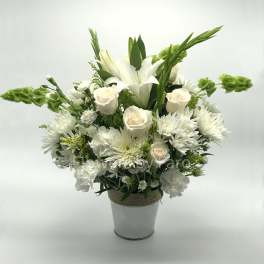 White and cream roses, lilies, and mums with green bells of Ireland in a white metal pot