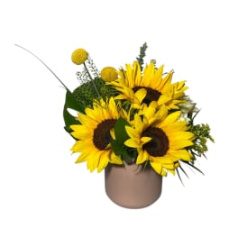 Sunflower arrangement in a beige vase with yellow accent blooms