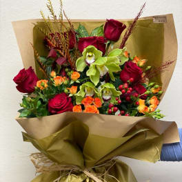 Bouquet of red roses and green orchids wrapped in gold paper