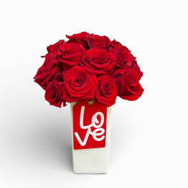 Red roses in a white vase with a red love tag