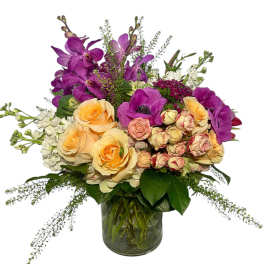 Mixed bouquet of purple orchids and peach roses in a glass vase