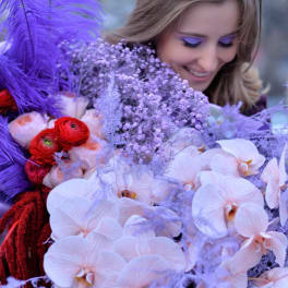 Woman holding a large bouquet of pale orchids and red flowers