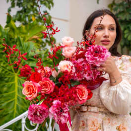 Woman holding a large bouquet of pink and red flowers