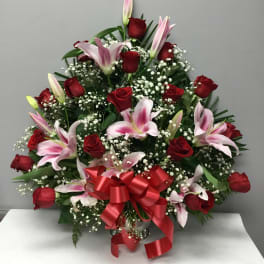 Red roses and pink lilies arranged with baby's breath and a red ribbon