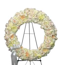 Cream floral wreath on a black stand with a silver ribbon