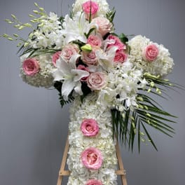 Large white floral cross with pink roses on an easel
