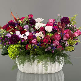Large mixed floral arrangement in a white ceramic container
