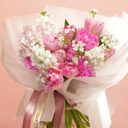 Pink tulip and peony bouquet with white blossoms wrapped in sheer paper