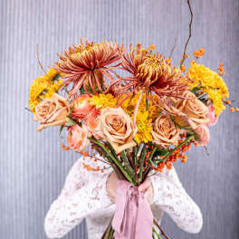 Handheld bouquet of peach roses and yellow chrysanthemums with a pink ribbon