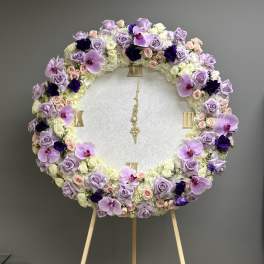 Large round floral wreath on an easel with lavender, white, and pink blooms