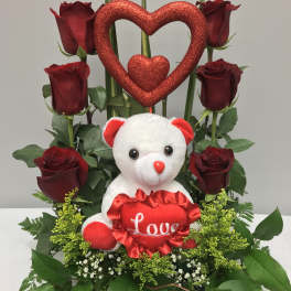 Red roses arranged with a teddy bear and glittery heart decoration