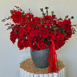Red rose and dahlia arrangement in a gray vase