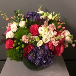 Mixed bouquet of roses, hydrangeas, and pink blooms in a vase