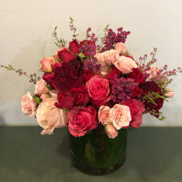 Red and pink roses arranged in a dark glass vase