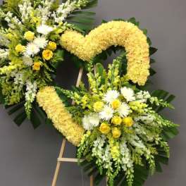 Two yellow and white floral wreaths on easels against a gray wall