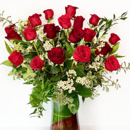 Red roses arranged in a glass vase with white filler flowers