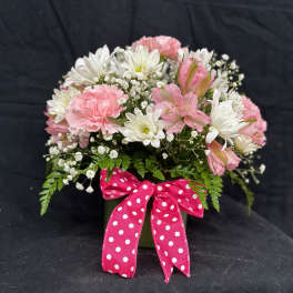 Pink and white flowers in a green vase with a polka-dot ribbon