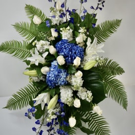 Tall blue and white floral spray with lilies, roses, and ferns