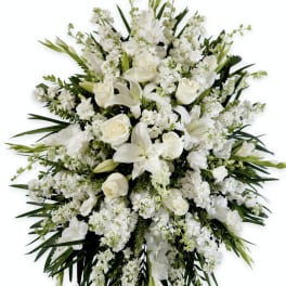 White floral standing spray with roses and lilies on an easel